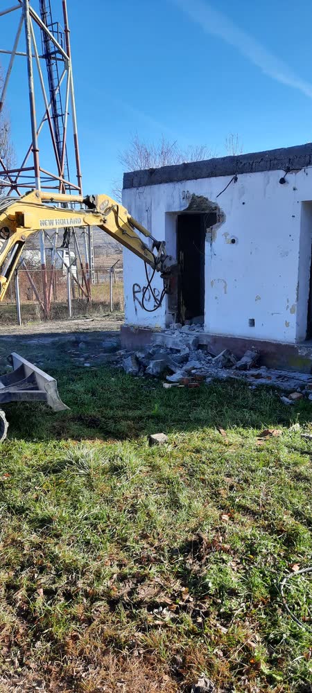 Un perete de beton spart cu utilajul, la demolarea unei construcții.