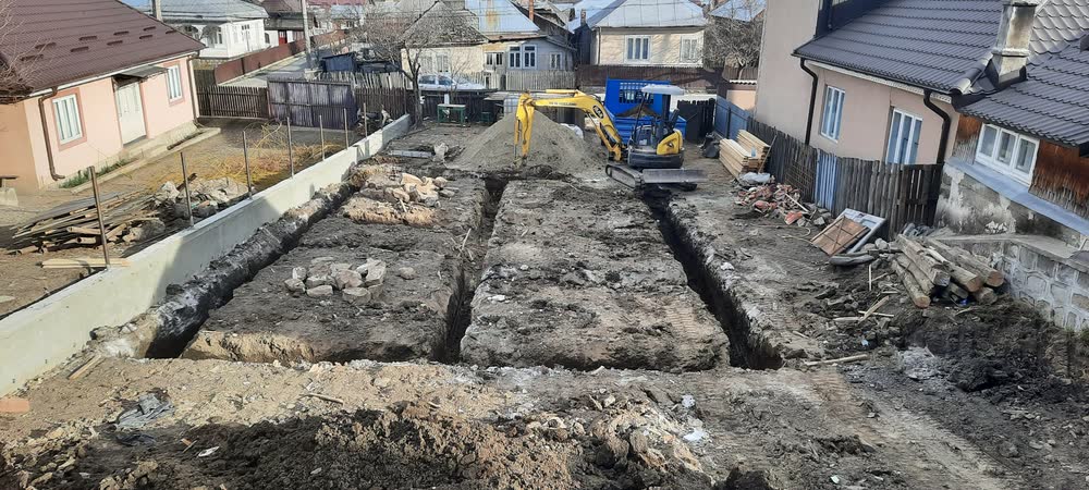 Șanț de fundație săpat pe trasaj, într-o curte strâmtă între două case.