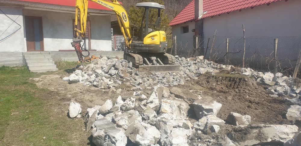 Platformă de beton spartă cu piconul hidraulic, lângă casă.